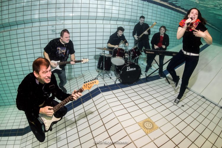 onderwater rockband gefotografeerd op de bodem van een zwembad.