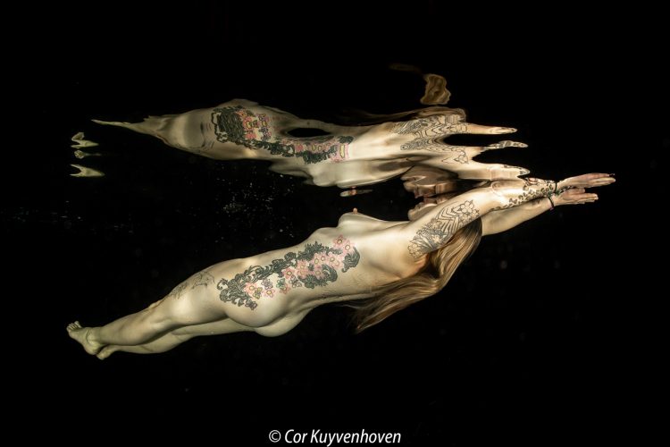 Naakte vrouw-tattoos-onderwater Naakte vrouw onder water met tattoos en zwarte achtergrond