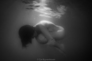Naakte vrouw in foetushouding onderwater