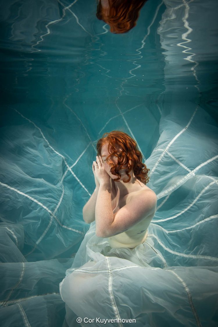Dame onder water met parachute Dame onderwater met parachute in zwembad.