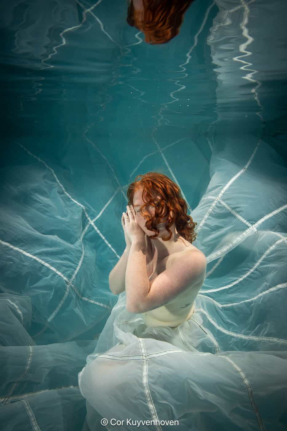 Dame onder water met parachute Dame onderwater met parachute in zwembad.